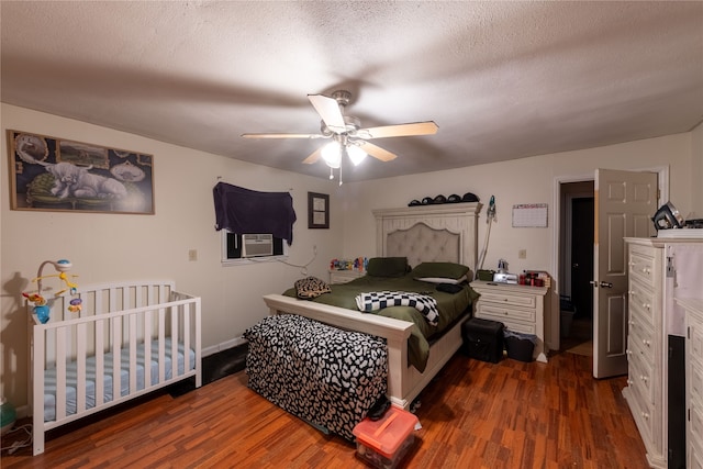 bedroom featuring cooling unit, a textured ceiling, dark wood-type flooring, and ceiling fan