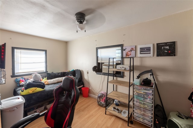 bedroom featuring light hardwood / wood-style floors, cooling unit, and ceiling fan