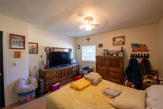 bedroom with ceiling fan, wood-type flooring, and a textured ceiling