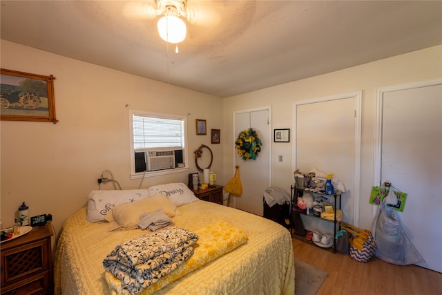 bedroom with ceiling fan, cooling unit, and hardwood / wood-style floors