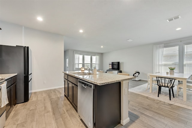 kitchen featuring sink, dishwasher, fridge, light hardwood / wood-style floors, and a kitchen island with sink