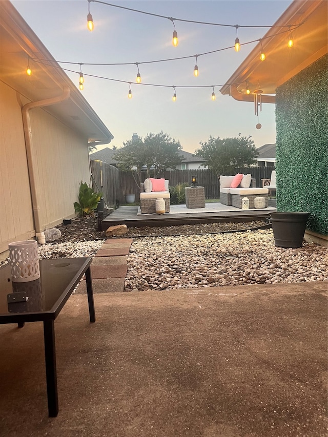 patio terrace at dusk featuring outdoor lounge area and a wooden deck