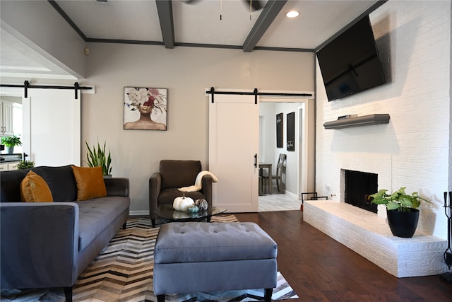 living room featuring beamed ceiling, hardwood / wood-style floors, a barn door, and a fireplace