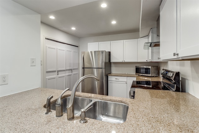 kitchen with appliances with stainless steel finishes, kitchen peninsula, white cabinetry, and sink