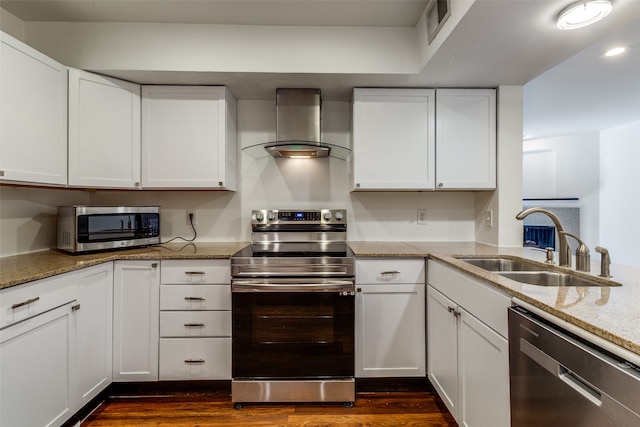 kitchen featuring wall chimney range hood, white cabinets, and stainless steel appliances