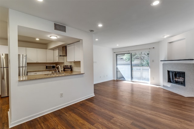 kitchen featuring light stone countertops, white cabinetry, stainless steel appliances, and dark hardwood / wood-style flooring