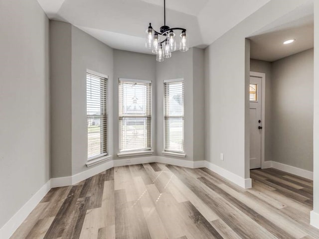 unfurnished dining area with a chandelier and light wood-type flooring