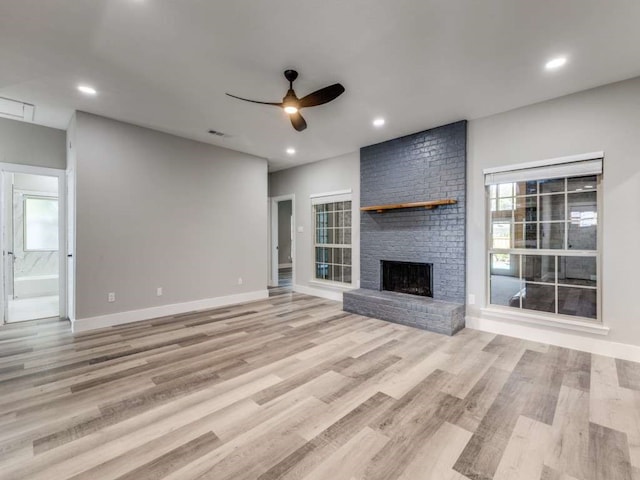 unfurnished living room with ceiling fan, light hardwood / wood-style flooring, plenty of natural light, and a fireplace