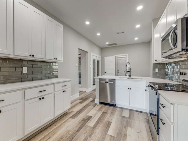 kitchen with sink, white cabinetry, light hardwood / wood-style flooring, and stainless steel appliances