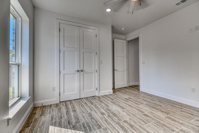 unfurnished bedroom featuring baseboards, ceiling fan, wood finished floors, and visible vents