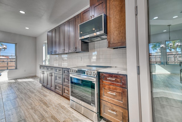kitchen with a notable chandelier, stainless steel appliances, baseboards, recessed lighting, and decorative backsplash