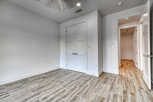 unfurnished bedroom with a ceiling fan, baseboards, wood finished floors, visible vents, and a closet