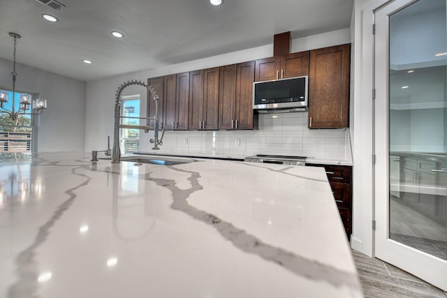 kitchen with recessed lighting, pendant lighting, stainless steel microwave, and tasteful backsplash