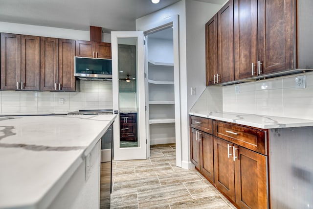 kitchen featuring dark brown cabinets, light stone countertops, tasteful backsplash, and light wood-type flooring