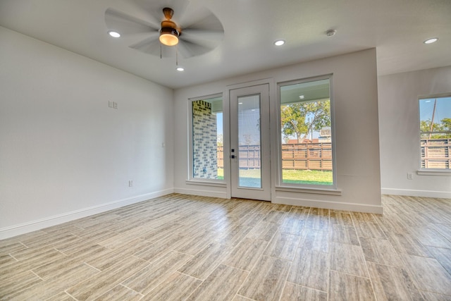 empty room with a healthy amount of sunlight, baseboards, a ceiling fan, and light wood-style flooring