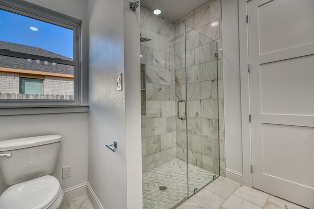 bathroom featuring toilet, baseboards, and a shower stall