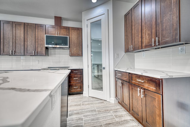 kitchen featuring light stone countertops, dark brown cabinetry, light wood-type flooring, and backsplash