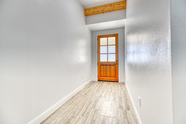 doorway to outside with beamed ceiling and light wood-type flooring