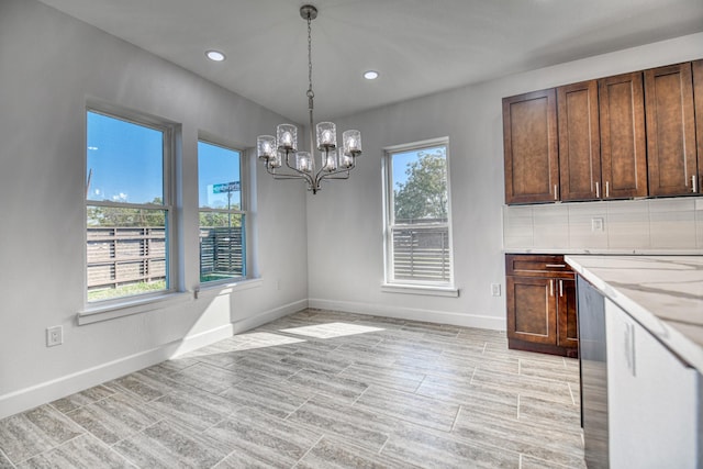 unfurnished dining area with baseboards, recessed lighting, and a chandelier