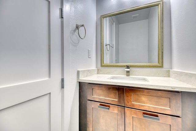 bathroom featuring a textured wall, visible vents, and vanity