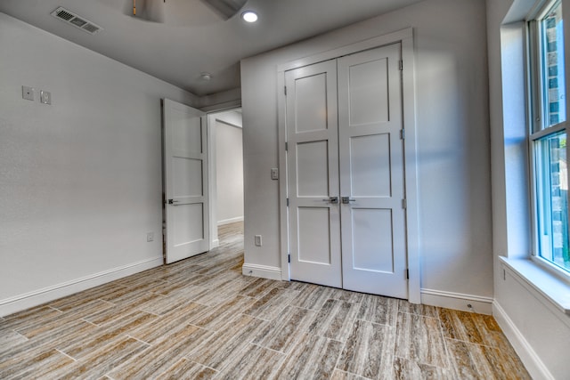 unfurnished bedroom with a closet, light hardwood / wood-style floors, and ceiling fan