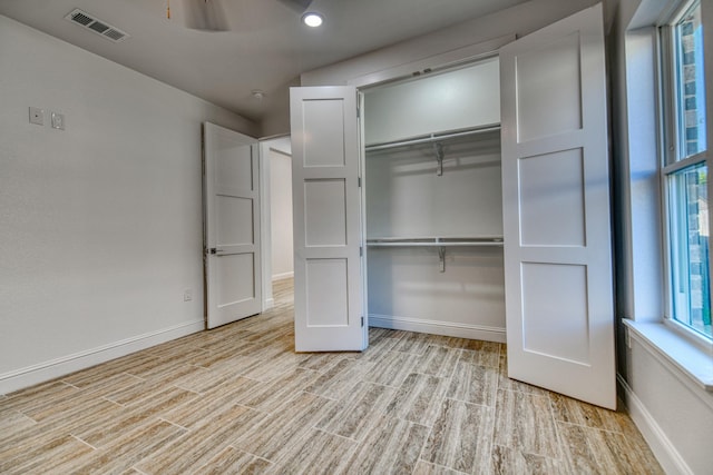 unfurnished bedroom with baseboards, a closet, light wood-style flooring, and visible vents