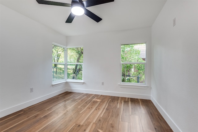 spare room featuring ceiling fan, hardwood / wood-style flooring, and plenty of natural light