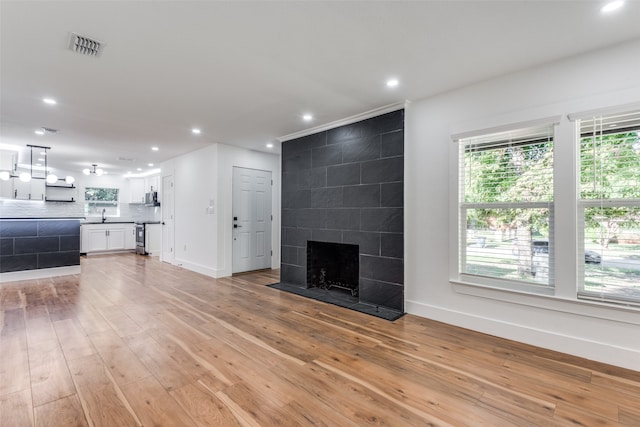 unfurnished living room featuring a tiled fireplace and light wood-type flooring