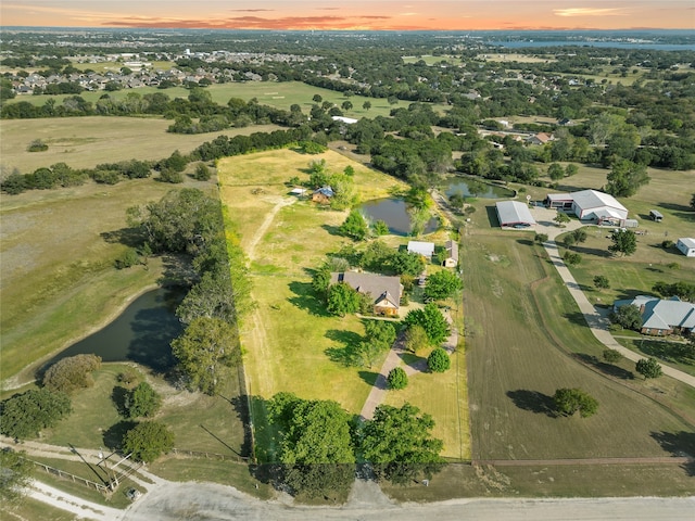 aerial view at dusk with a water view and a rural view