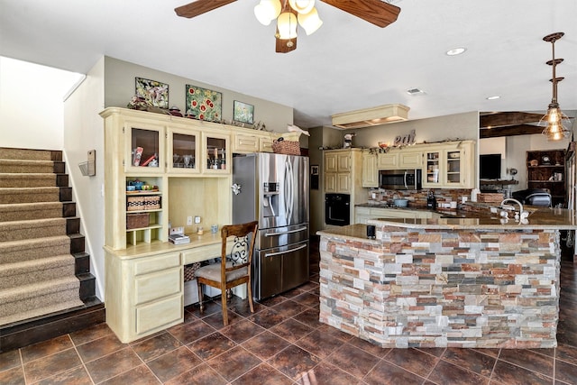 kitchen featuring tasteful backsplash, cream cabinets, hanging light fixtures, built in desk, and stainless steel appliances