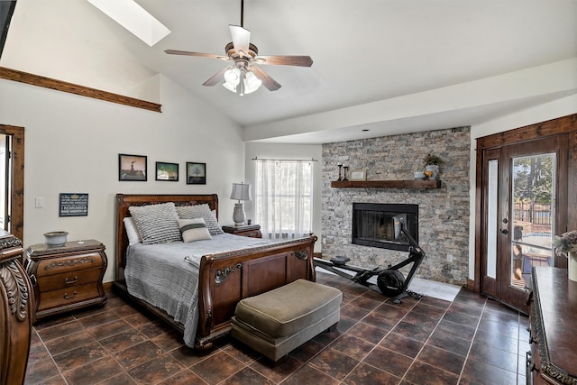 bedroom with ceiling fan, a skylight, multiple windows, and a fireplace