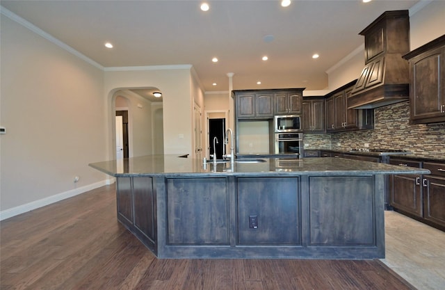 4095 Bridgecreek Dr, Rockwall, TX 75032 - kitchen featuring crown molding, dark brown cabinets, decorative backsplash, a large island with sink, and stainless steel appliances