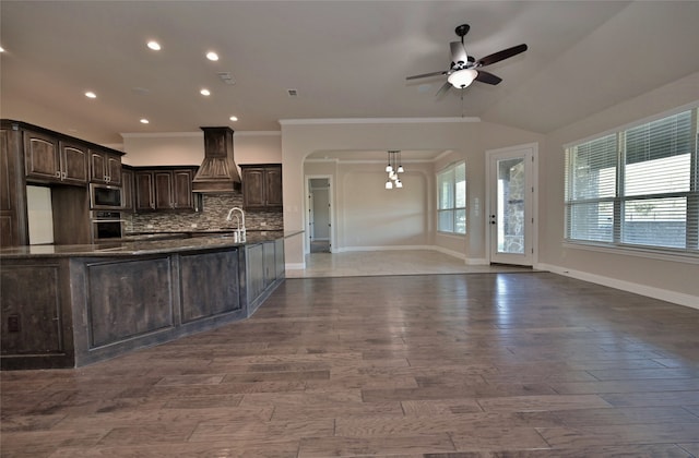 kitchen featuring custom exhaust hood, tasteful backsplash, dark brown cabinets, crown molding, and stainless steel appliances