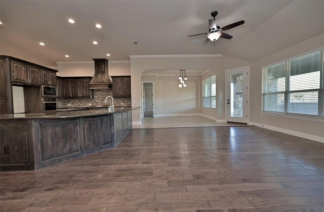 4095 Bridgecreek Dr, Rockwall, TX 75032 - kitchen with tasteful backsplash, dark brown cabinets, custom exhaust hood, ceiling fan, and appliances with stainless steel finishes
