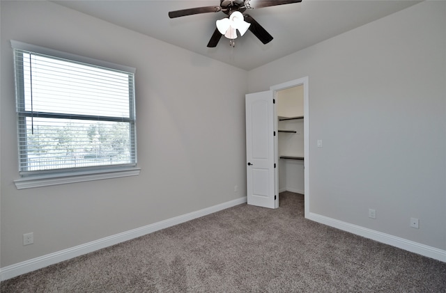 unfurnished bedroom with a spacious closet, ceiling fan, a closet, and light colored carpet