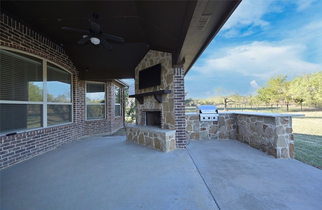 view of patio with ceiling fan, an outdoor stone fireplace, and grilling area