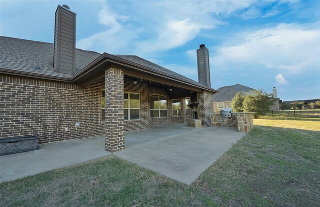 4095 Bridgecreek Dr, Rockwall, TX 75032 - rear view of house with brick siding, area for grilling, a chimney, and a lawn