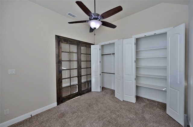 unfurnished bedroom featuring lofted ceiling, carpet, multiple closets, and ceiling fan