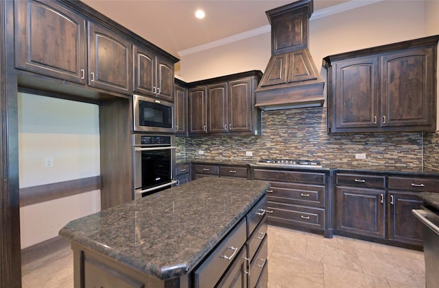 kitchen featuring dark brown cabinets, backsplash, dark stone counters, ornamental molding, and appliances with stainless steel finishes