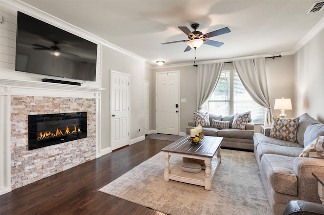 living room with ornamental molding, ceiling fan, a stone fireplace, and dark hardwood / wood-style flooring