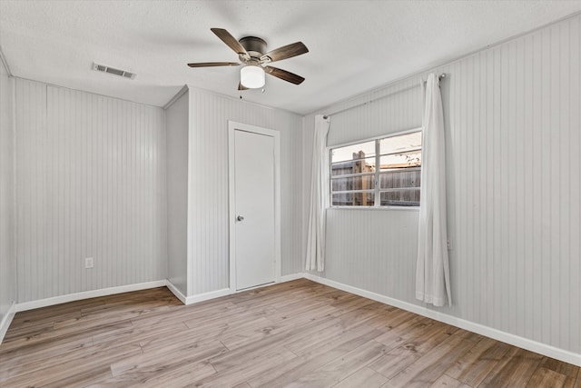 empty room featuring ceiling fan, a textured ceiling, and light wood-type flooring