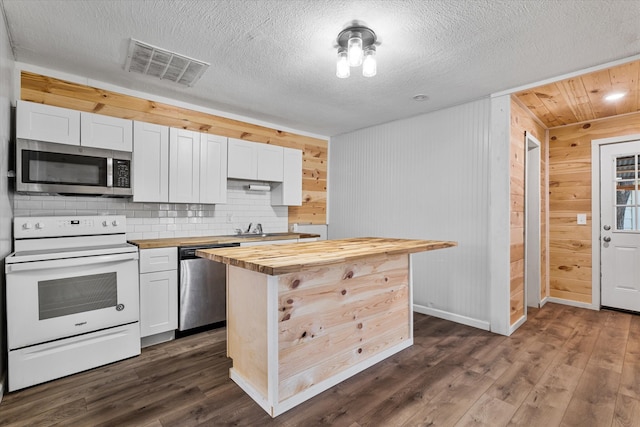 kitchen featuring butcher block counters, dark wood-type flooring, white cabinets, appliances with stainless steel finishes, and wood walls