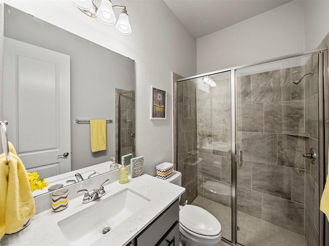 bathroom with vanity, toilet, a textured wall, and a stall shower