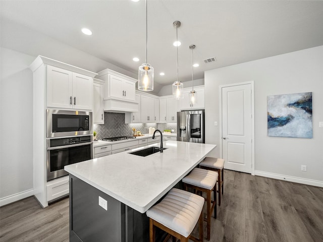 kitchen featuring dark wood-style floors, visible vents, a sink, appliances with stainless steel finishes, and backsplash