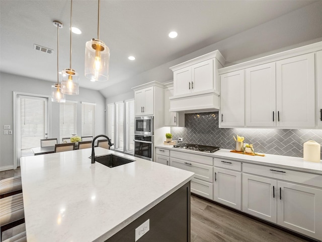 kitchen featuring visible vents, a sink, white cabinetry, stainless steel appliances, and a breakfast bar area