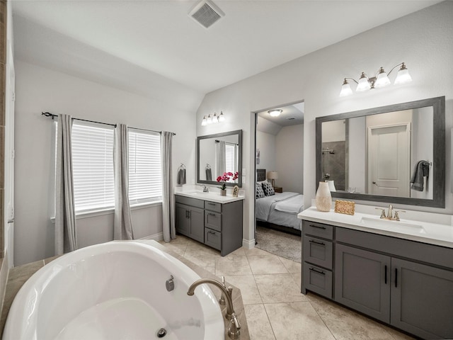 bathroom featuring a bathing tub, visible vents, lofted ceiling, and a sink