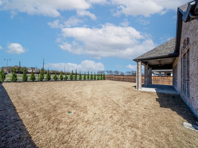 view of yard featuring ceiling fan, a patio, and a rural view