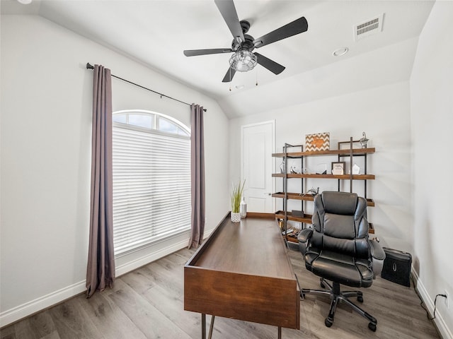 office space with vaulted ceiling, wood finished floors, baseboards, and visible vents