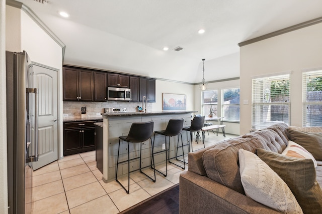 kitchen with backsplash, pendant lighting, a breakfast bar area, a center island with sink, and appliances with stainless steel finishes