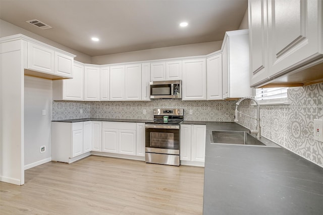 kitchen with tasteful backsplash, sink, light hardwood / wood-style floors, stainless steel appliances, and white cabinets